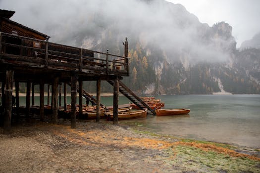 宁静的湖边薄雾中，山脉和雾霭笼罩着木船与码头