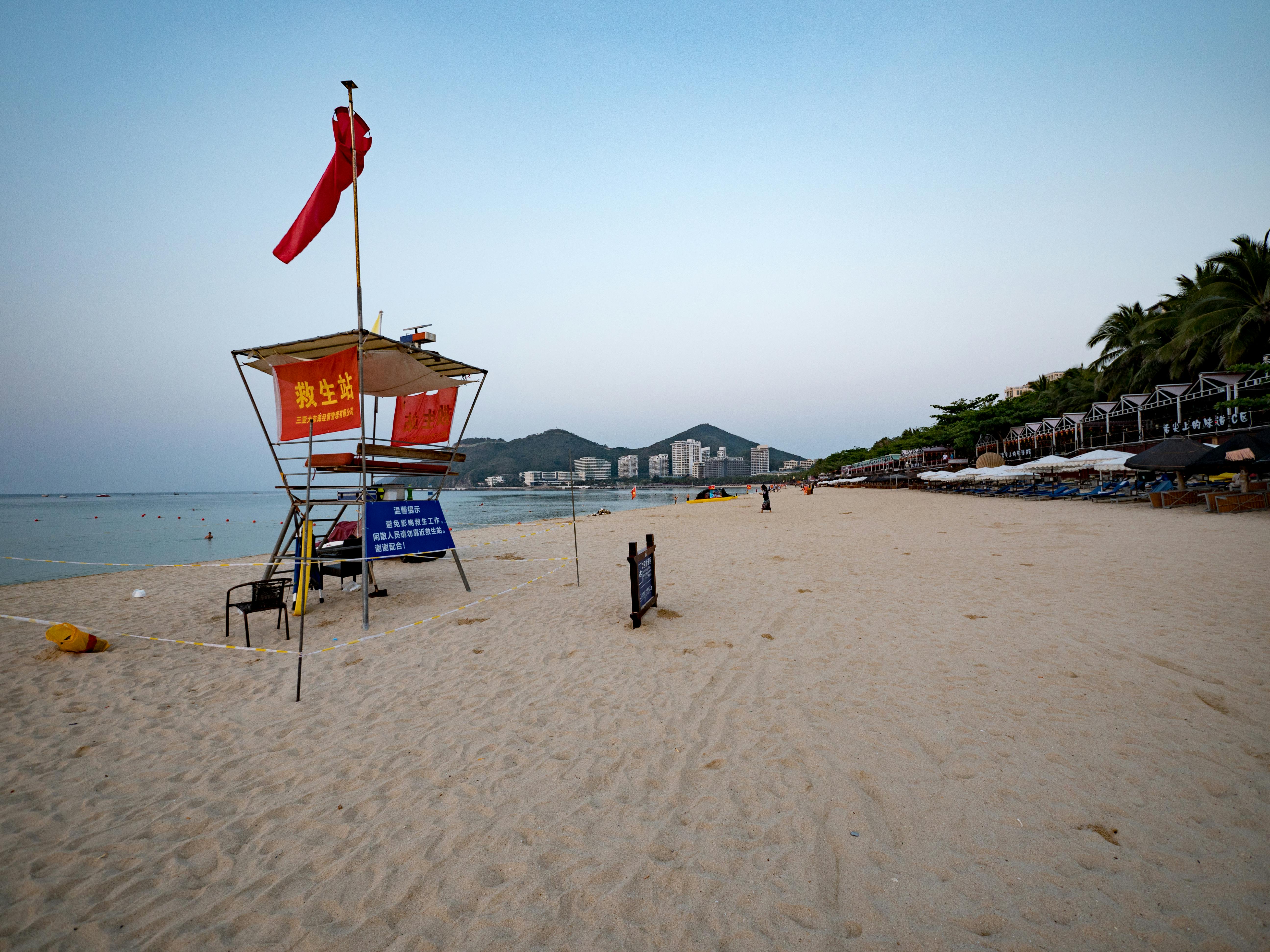 Serene beach scene in Sanya, China featuring a lifeguard tower and clear blue sky.
