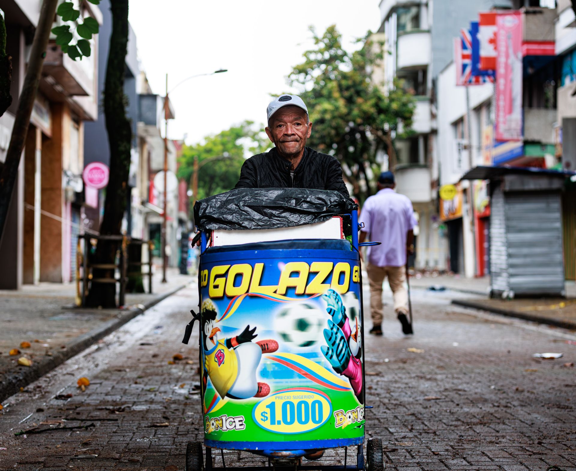 Street vendor in Pereira pushes colorful ice cream cart, lively urban scene.