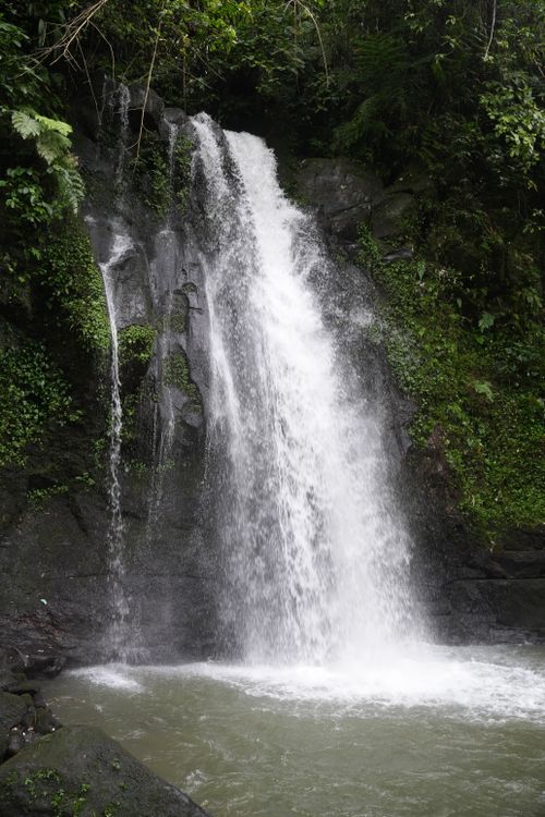 Free A beautiful waterfall cascading down rocky terrain surrounded by lush greenery in Bali, Indonesia. Stock Photo