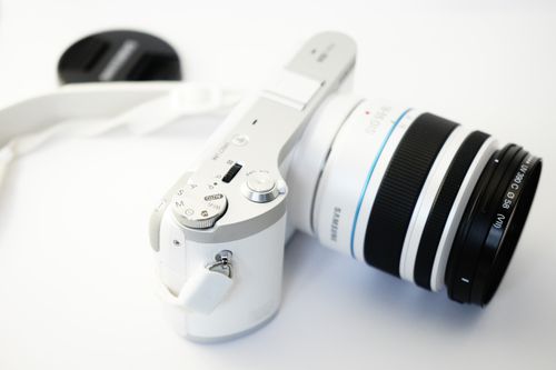 Free Close-up of a white mirrorless camera and detached lens cap on a white background. Stock Photo