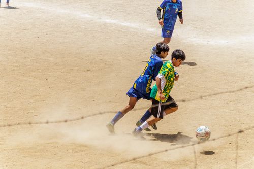 Free Young players in action during a competitive soccer game on a dusty outdoor field. Stock Photo