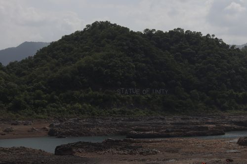 Free Lush green hills and calm waters with Statue Of Unity inscription on hillside. Stock Photo