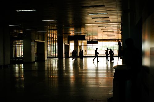Free Silhouetted people walking through a contemporary airport terminal at dusk. Stock Photo