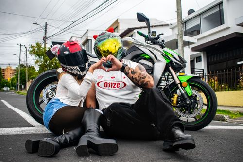 Free Couple in helmets express love while sitting on the road with a motorcycle. Stock Photo