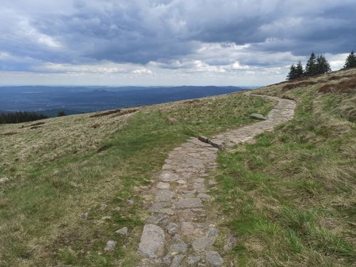 Free A stone path leads through a grassy hillside with a dramatic cloudy sky. Stock Photo