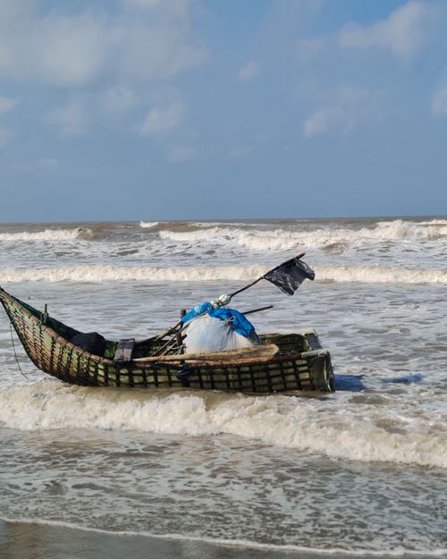 Free A traditional fishing boat rests on the waves at Cox's Bazar, capturing the essence of Bangladeshi coastal life. Stock Photo