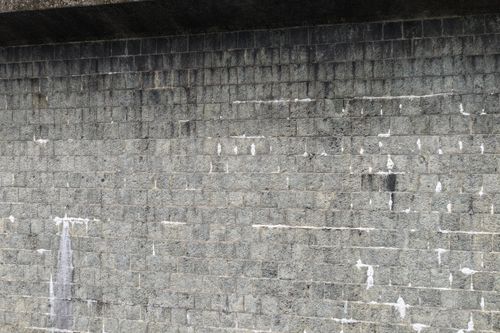 Free Close-up of a worn gray stone wall exterior with visible texture and weather wear. Stock Photo