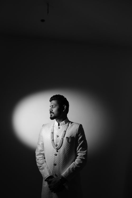 Free Black and white portrait of a man thoughtfully gazing in traditional attire, spotlight effect. Stock Photo