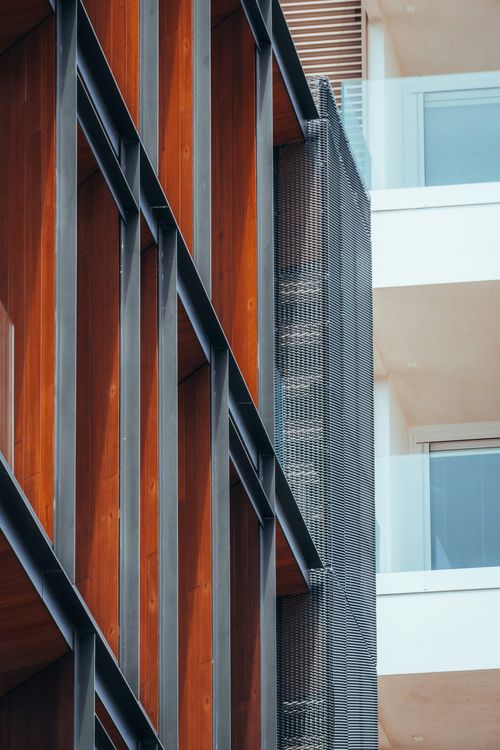 Free Close-up of a modern urban building facade featuring wood, metal, and glass elements. Stock Photo