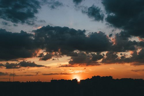 Free Beautiful sunset over a city skyline with dramatic clouds. Stock Photo