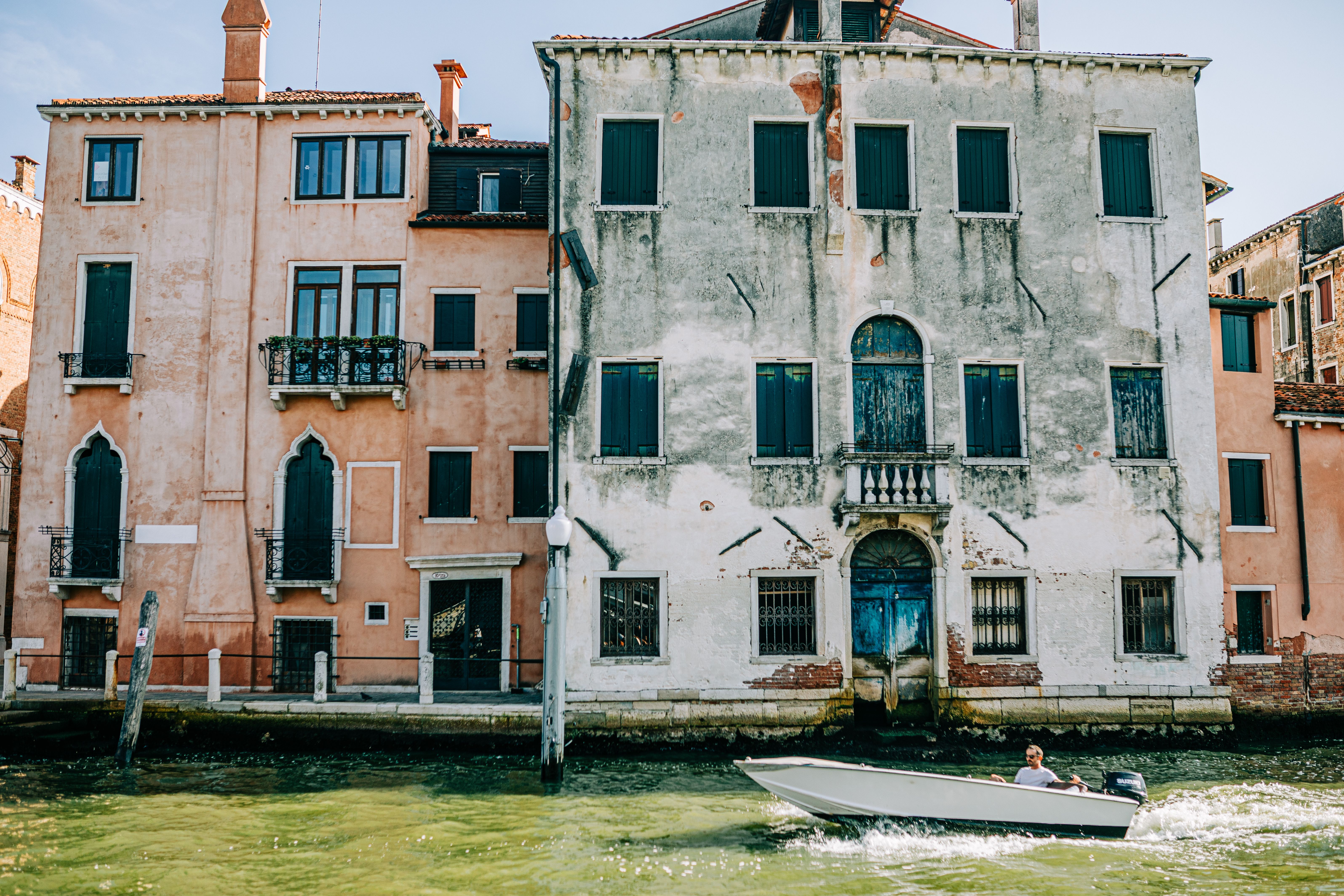 Charming view of Venetian architecture along a canal, featuring a motorboat on a sunny day.
