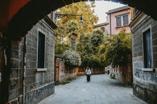 A picturesque alleyway in a European city, framed by rustic architecture and lush greenery.