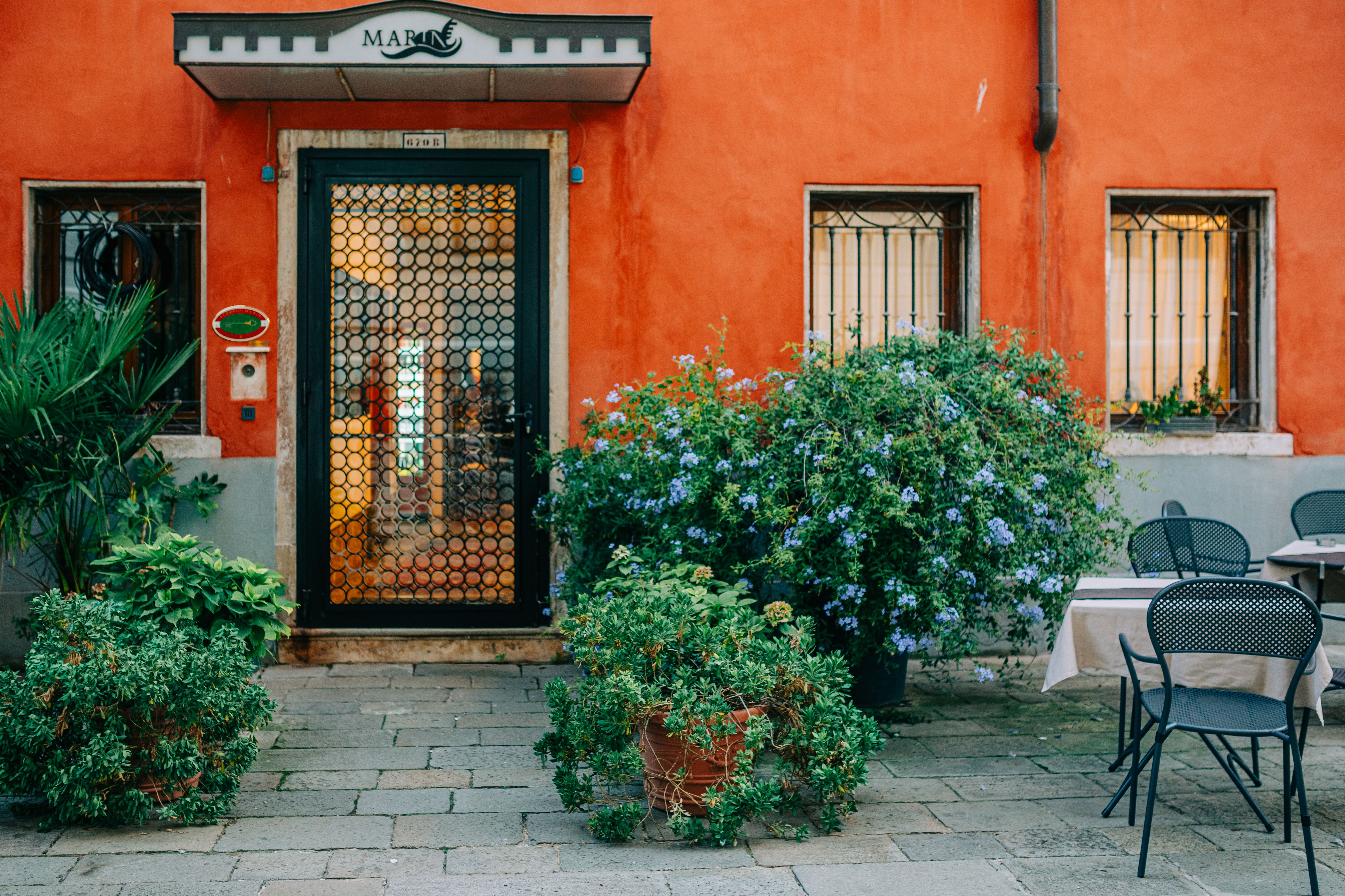 The front of a narrow townhouse with a painted door and a parking space in front
