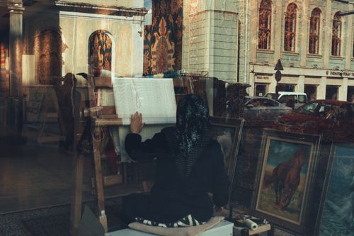 Free A traditional artisan weaving carpets, captured through a shop window in Istanbul, Türkiye. Stock Photo