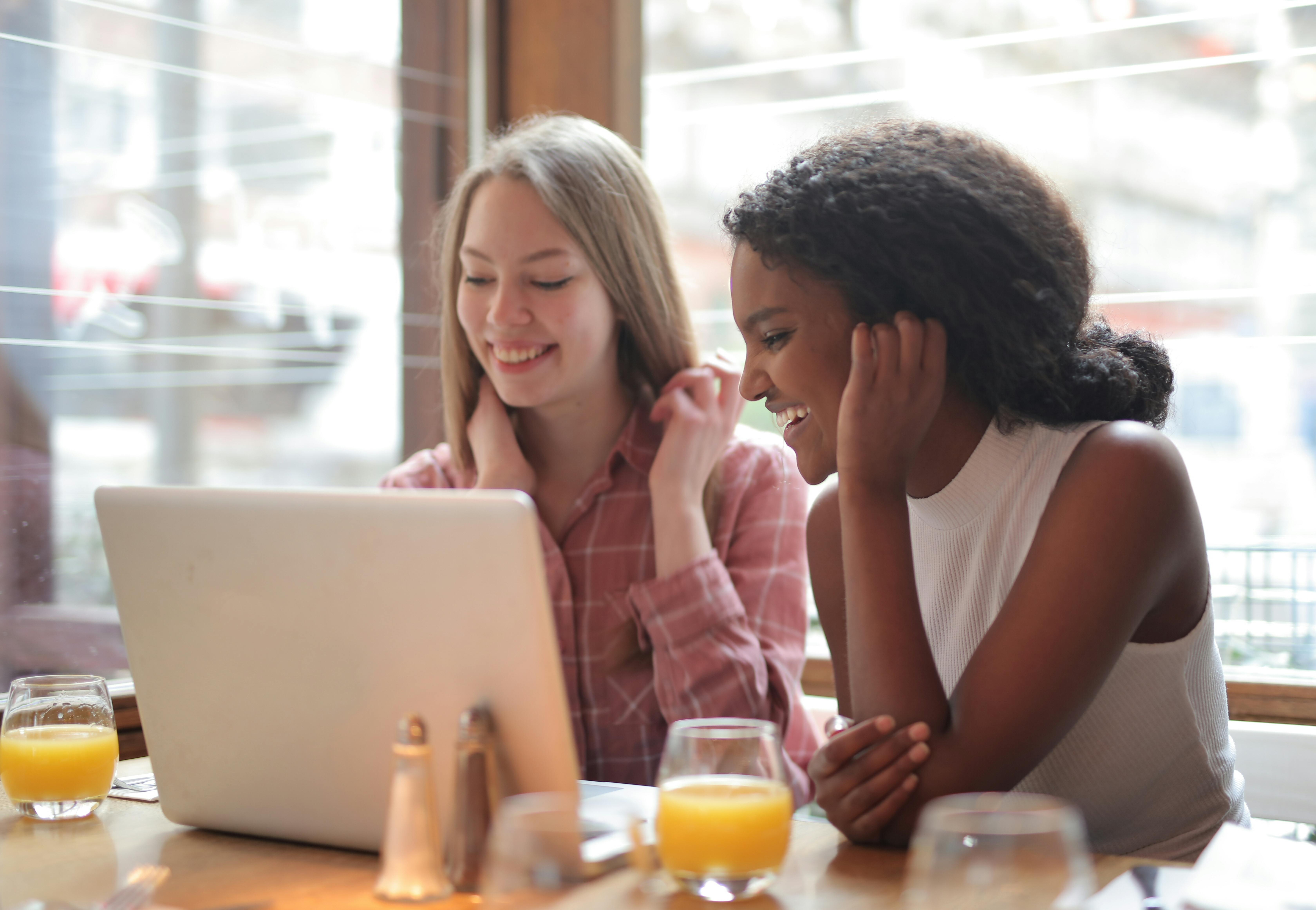 Two girls smiling and looking at laptop