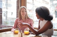 两个女人在咖啡馆边喝橙汁边聊天，展现了完美的友谊和休闲氛围