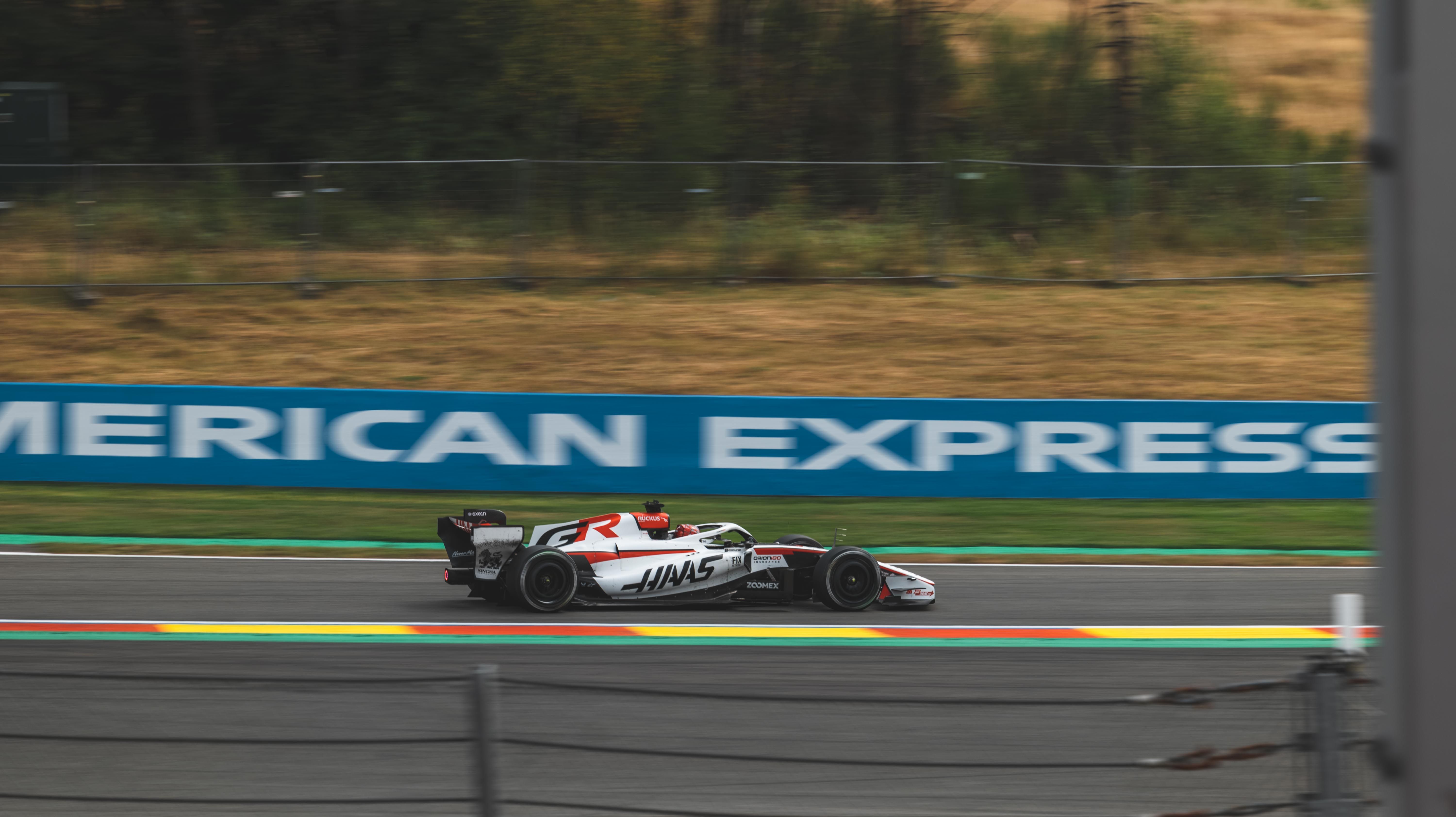Dynamic shot of a Haas F1 car racing on a track at Spa-Francorchamps, Belgium.