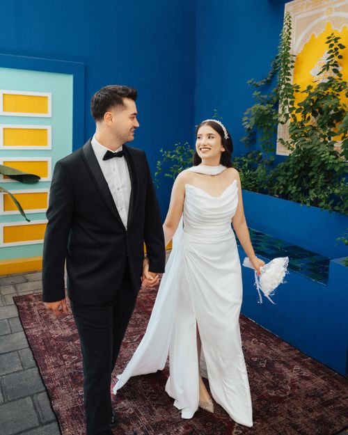 Free Bride and groom holding hands in a vibrant Antalya courtyard, showcasing joy and love. Stock Photo