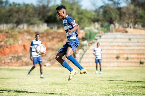 Free A young soccer player executes a jumping kick on an outdoor field during a sunny day match. Stock Photo