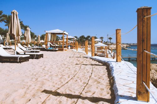 Free Sunny beach resort scene with lounge chairs, cabanas, and umbrellas by the sea on a clear day. Stock Photo