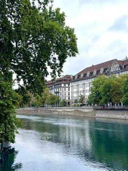 Peaceful riverside view in Zurich with classic European architecture and lush greenery.