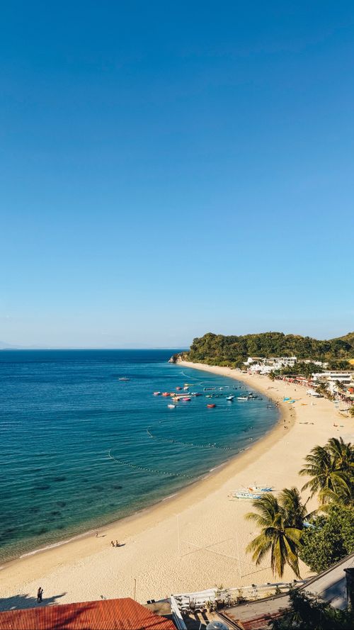 Free Idyllic beach scene in Puerto Galera, Philippines, showcasing clear skies and calm waters. Stock Photo