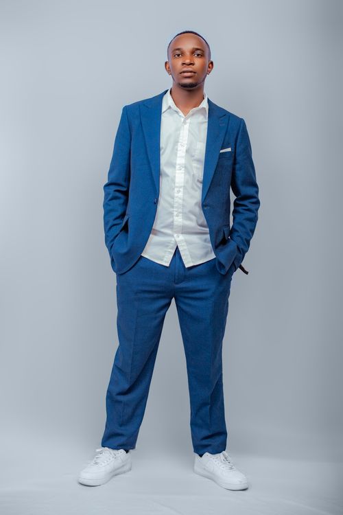 Free Stylish young man wearing a blue suit and white sneakers, posing confidently indoors. Stock Photo