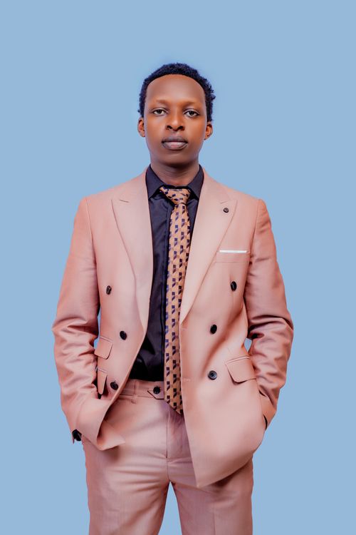 Free A stylish man in a peach suit poses confidently against a light blue background, exuding elegance. Stock Photo