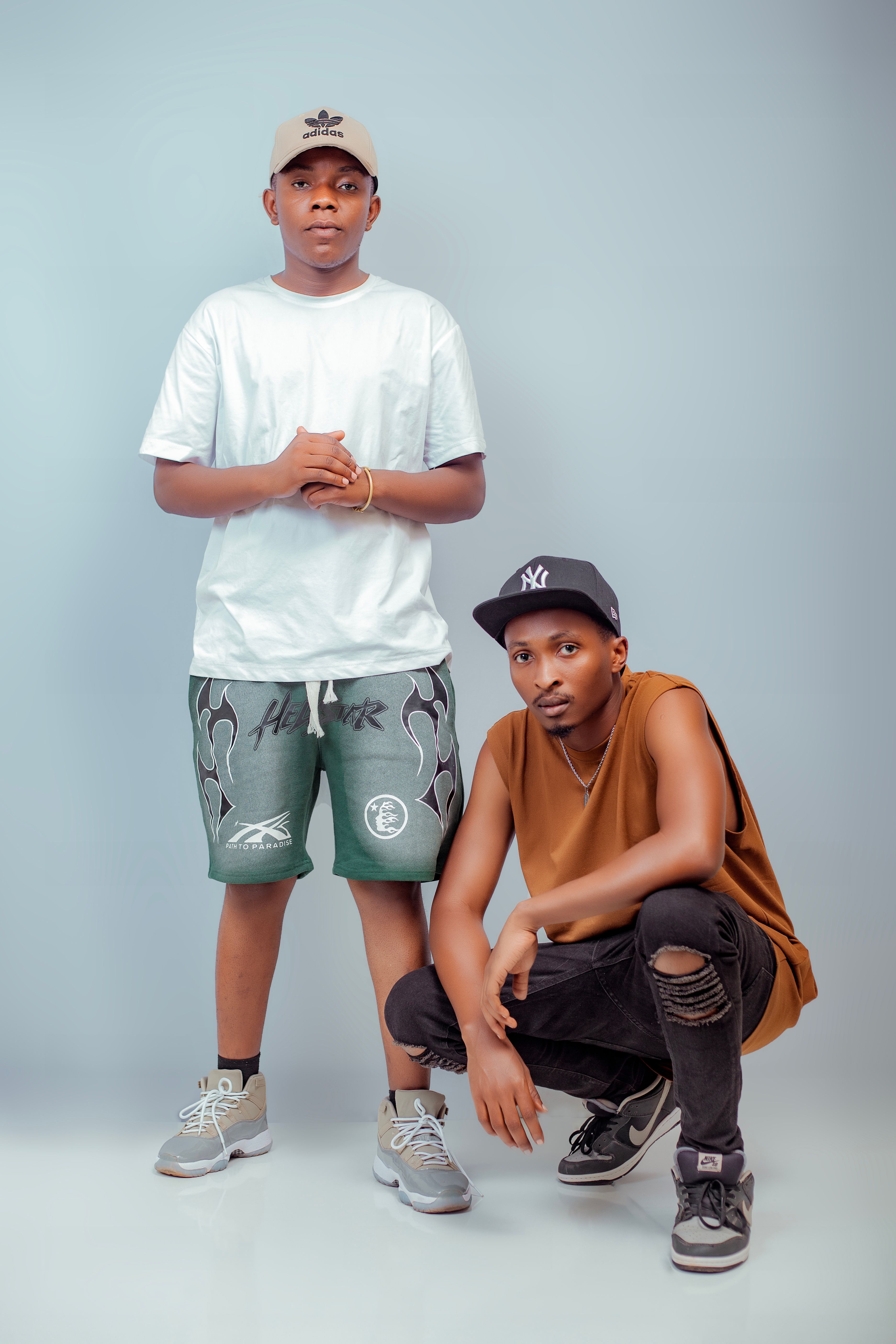 Young men in casual streetwear posing against a plain backdrop, illustrating modern urban fashion.