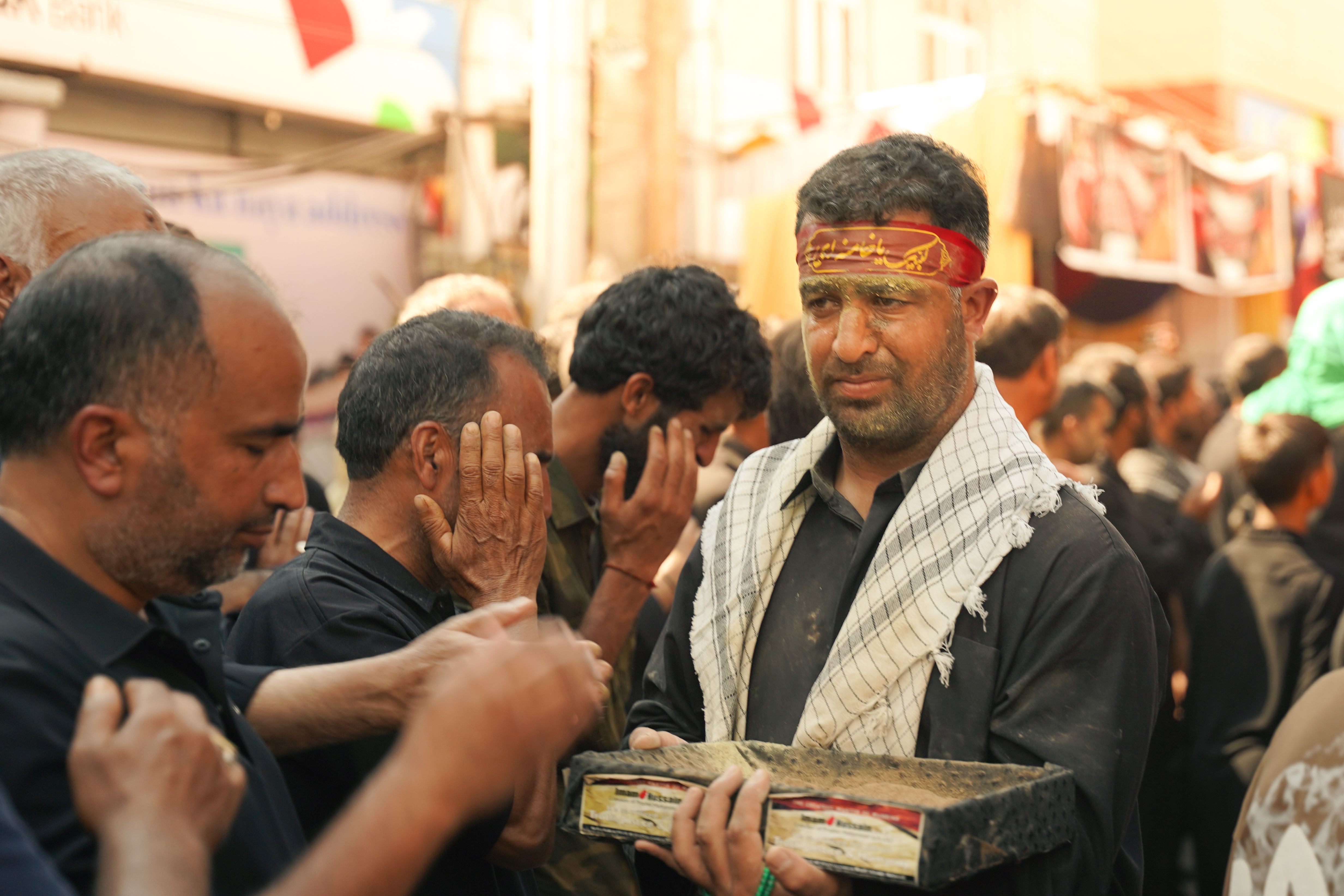 Group of men engaged in a solemn religious procession holding a tray.