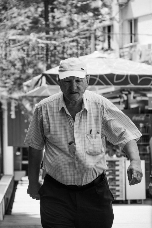 Free Black and white photo of an elderly man in a bustling outdoor market scene. Stock Photo