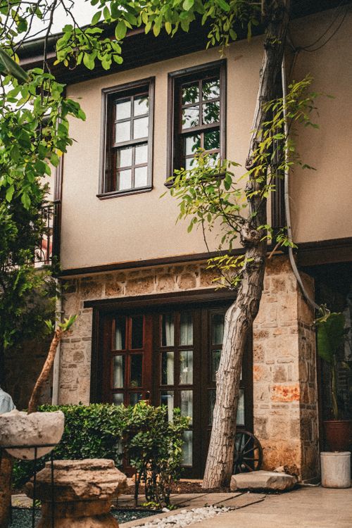 Free A picturesque view of a rustic stone and wood house tucked in a lush green garden setting. Stock Photo