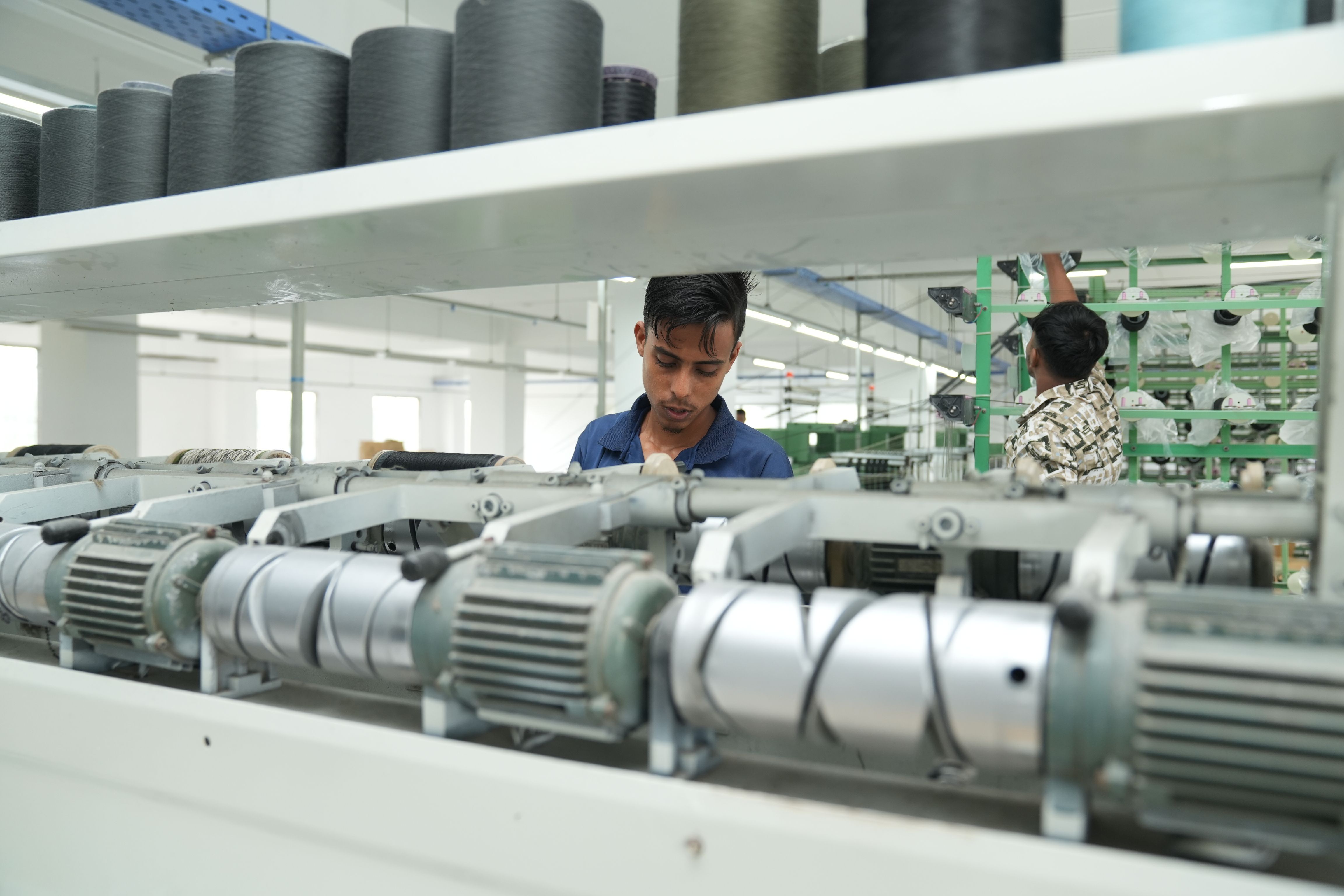Industrial factory interior with workers operating textile machinery