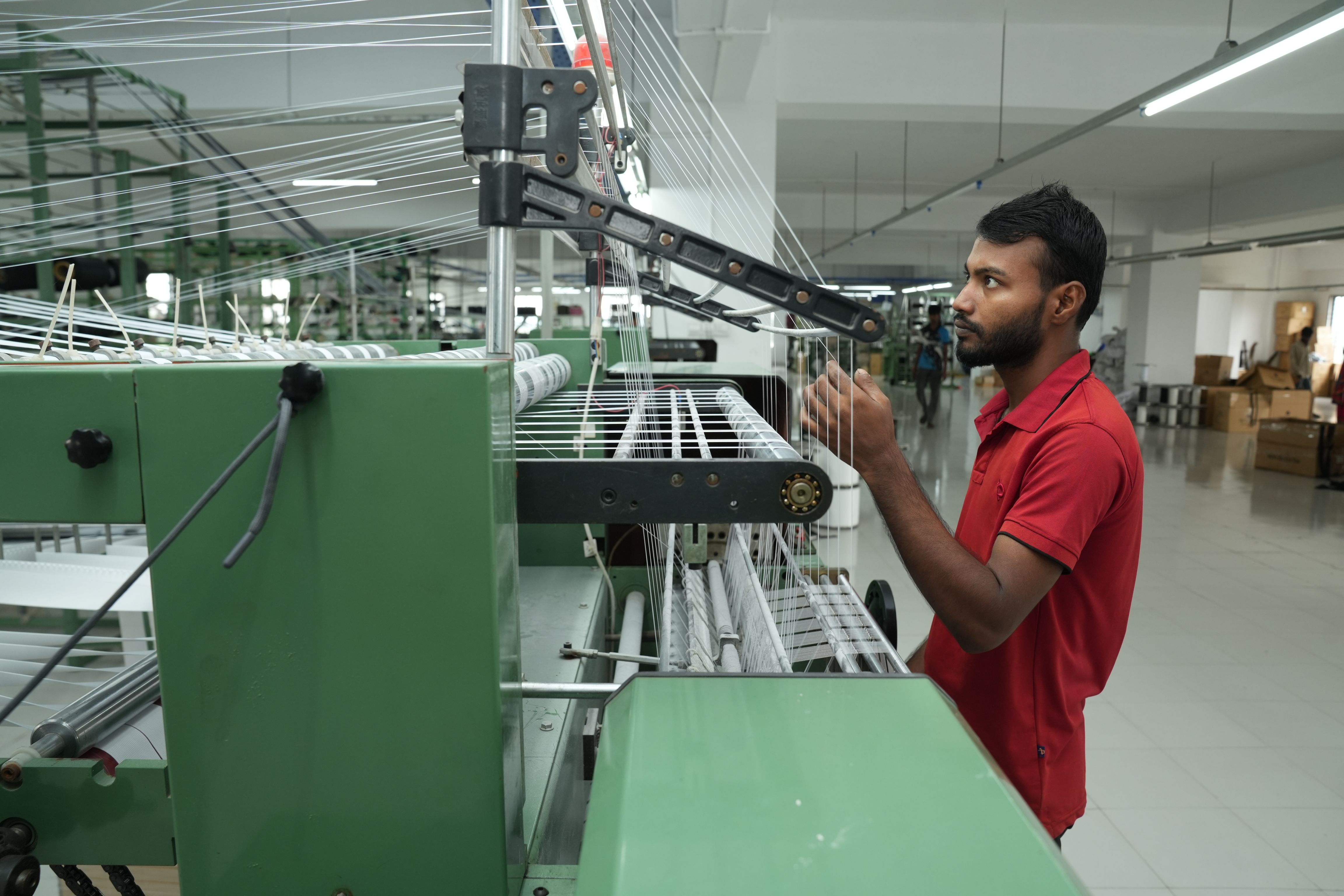Man operating a weaving machine on a textile factory production line.