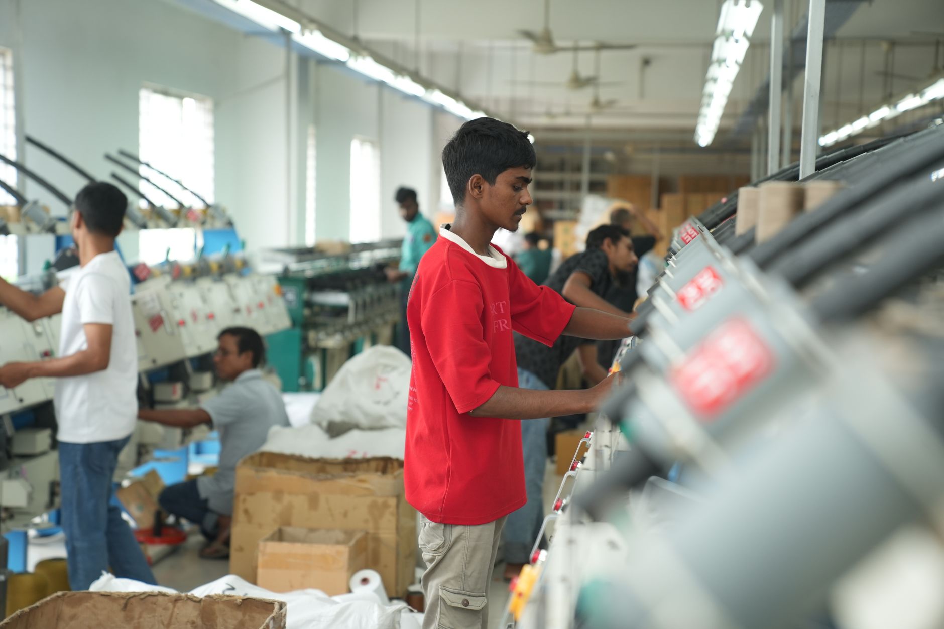Workers in a textile factory operating machinery, focusing on production efficiency.