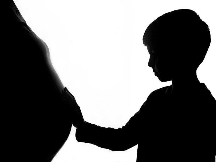 Silhouette Of A Boy Holding Baby Bump