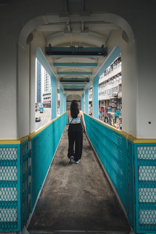 Free A woman walks alone on a vibrant pedestrian bridge in Hong Kong, showcasing city life. Stock Photo