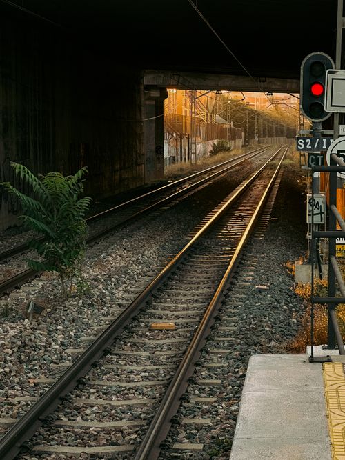 Free Sunlit railway tracks leading into a tunnel during sunset in Spain. Stock Photo