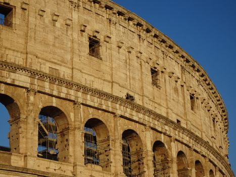 Close-up of the Colosseum's ancient architecture in Rome, bathed in warm golden hour light.