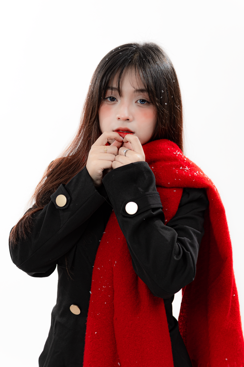 Free Portrait of a young woman in winter attire, featuring a bold red scarf and snowflakes. Stock Photo