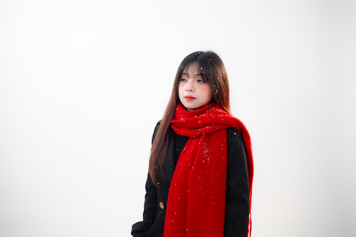 Free Portrait of a woman wearing a red scarf, gazing thoughtfully with snowflakes on her. Stock Photo