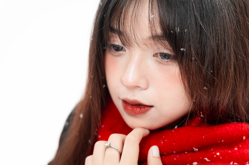 Free Close-up portrait of a woman with snowflakes wearing a red scarf, evoking winter serenity. Stock Photo