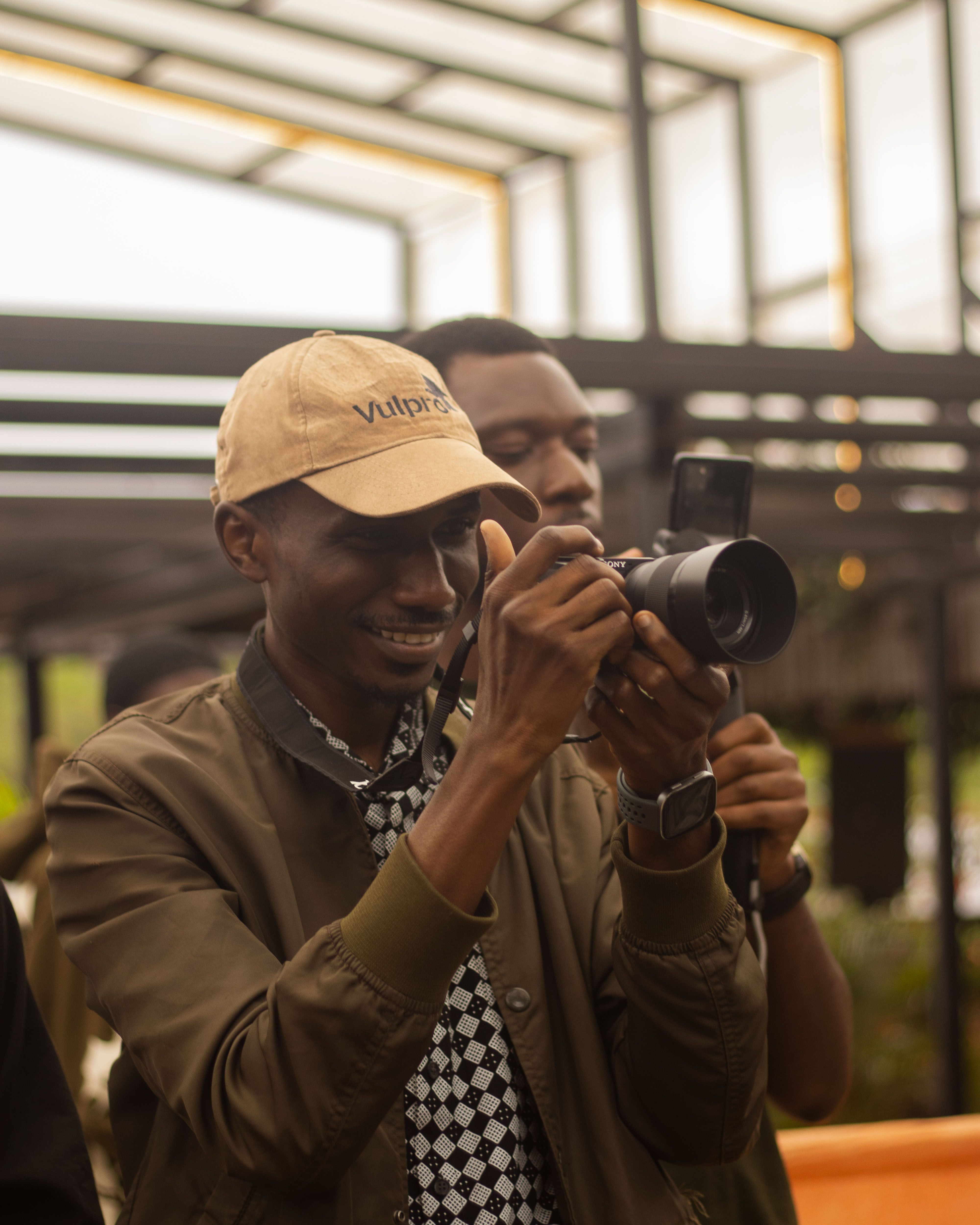 A joyful photographer focused on capturing the perfect shot in an urban setting in Jos, Nigeria.