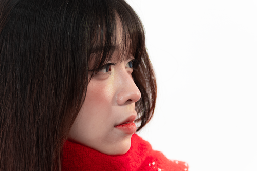 Free Close-up side profile of a young woman wearing a red scarf against a white background. Stock Photo