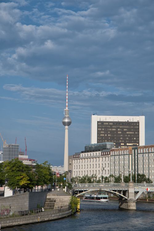 Free Scenic view of Berlin TV Tower alongside the Spree River under a vibrant blue sky. Stock Photo