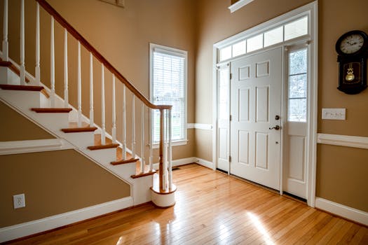 A bright and elegant entrance featuring a wooden staircase and classic interior design.