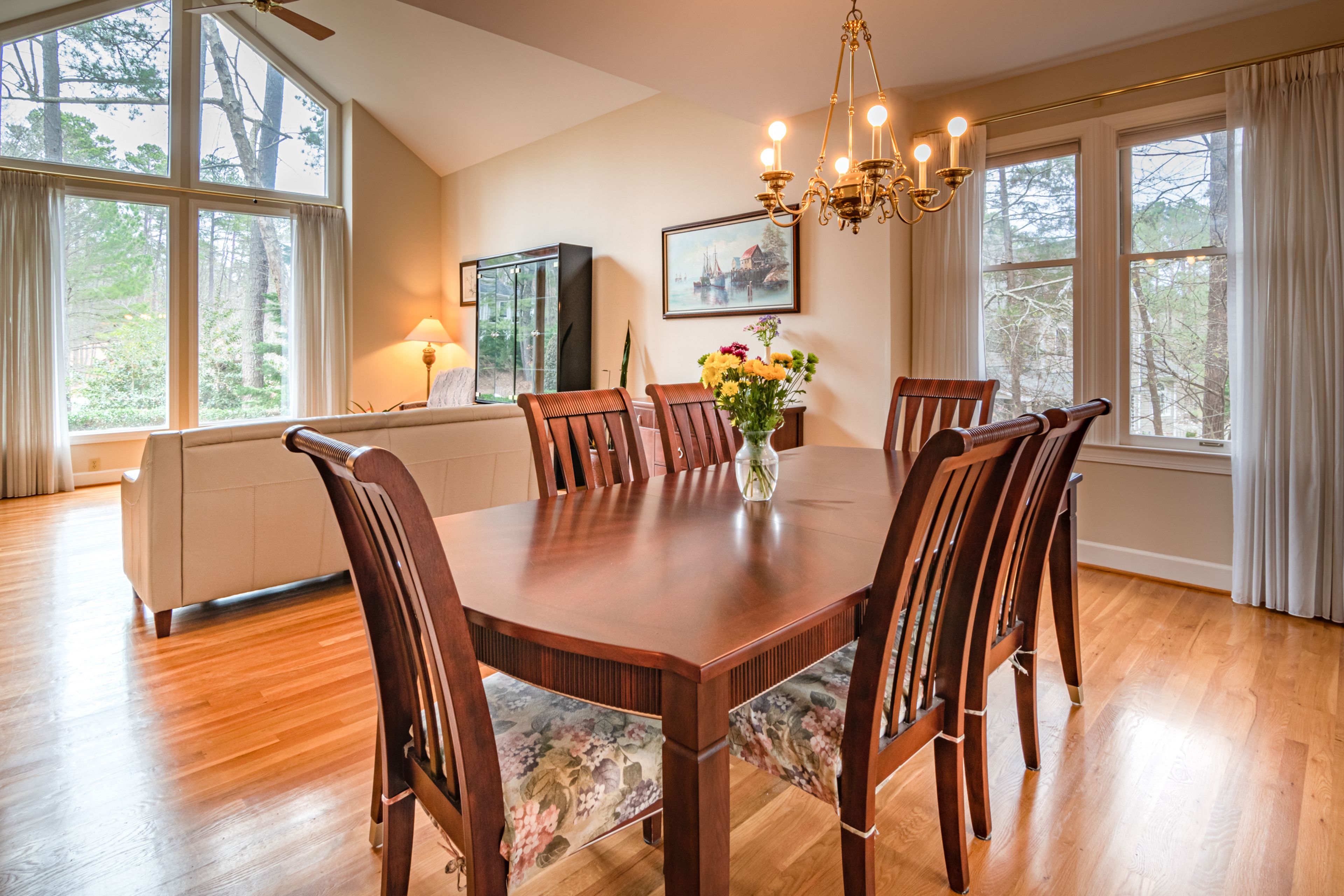 A dining room with wooden table and chairs on a polished wood floor