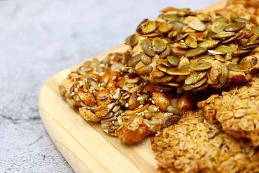 Close-up of various healthy homemade mixed nut and seed snacks on a wooden board.