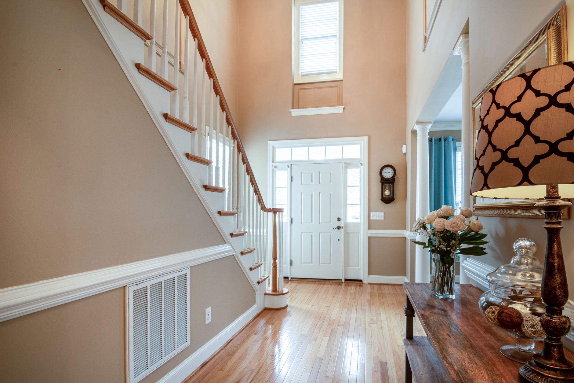 Sophisticated home entrance with staircase, wooden flooring, and elegant decor.